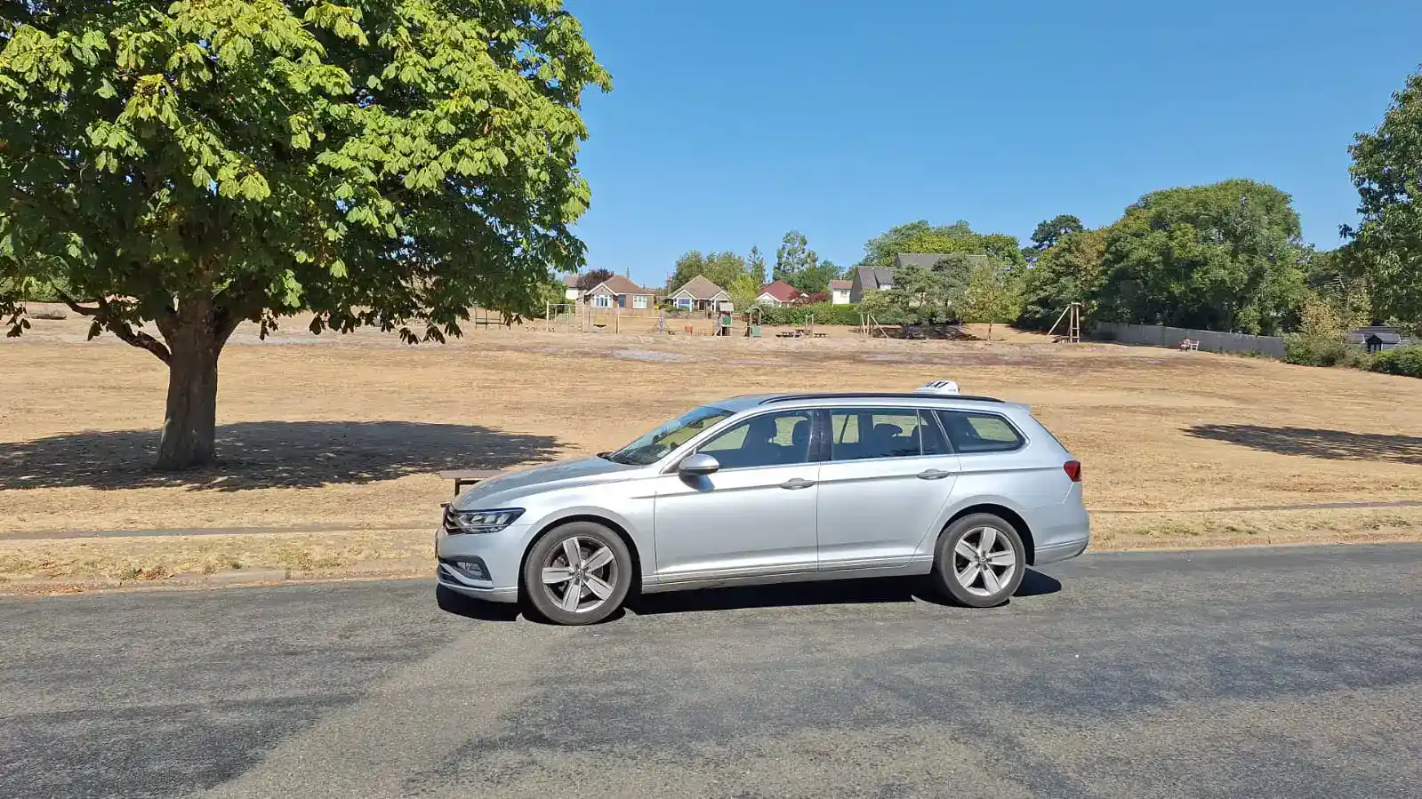 Silver G and M Taxis estate parked beside a village green, used for Train Station Taxi in Downham Market and surrounding Norfolk village journeys.