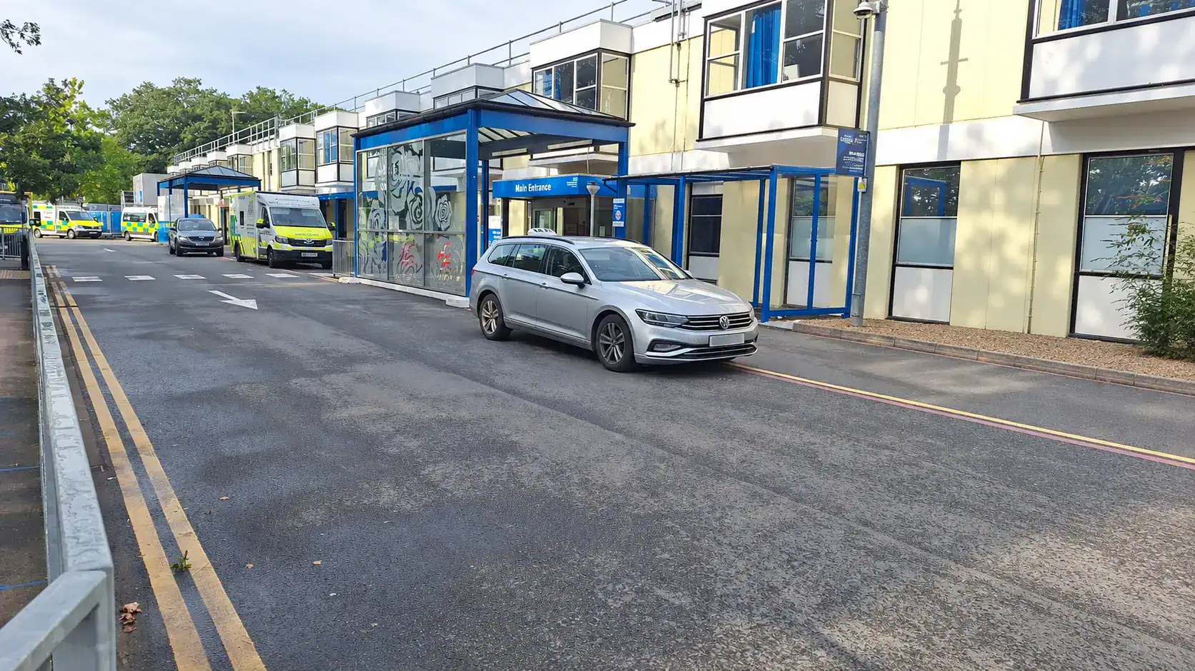 Silver G and M Taxis estate car waiting outside a hospital entrance for a pre-booked Taxi for Hospital Downham Market journey.